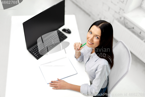 Image of businesswoman writing to notebook at office