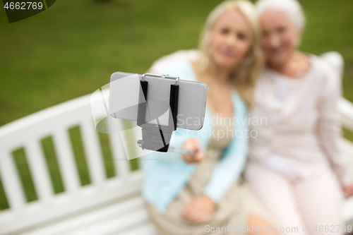 Image of daughter and senior mother taking selfie at park