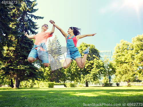 Image of happy teenage couple jumping at summer park