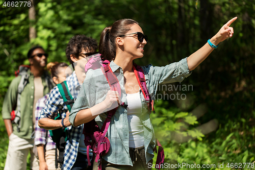 Image of group of friends with backpacks hiking in forest