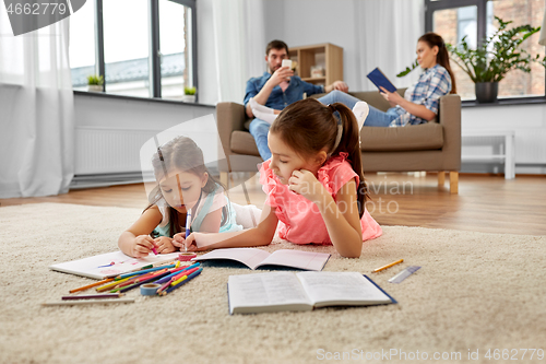 Image of happy sisters drawing and doing homework at home