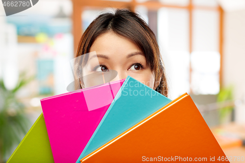 Image of asian woman or student hiding behind notebooks