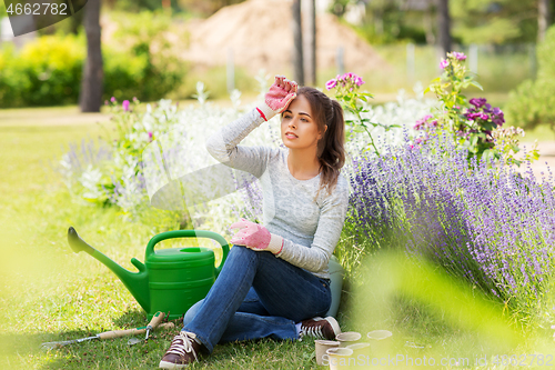 Image of tired young woman with garden tools in summer