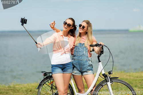 Image of teenage girls with bicycle taking selfie in summer