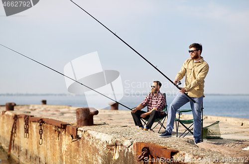 Image of happy friends with fishing rods on pier