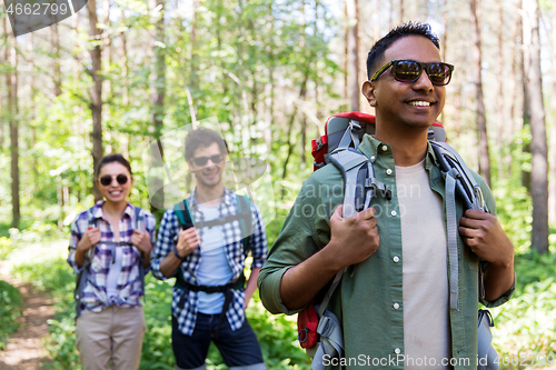 Image of group of friends with backpacks hiking in forest