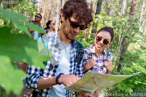 Image of friends with map and backpacks hiking in forest