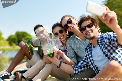 Image of friends with drinks taking selfie by smartphone