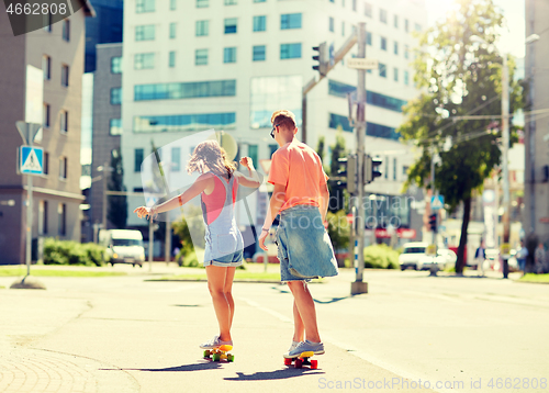 Image of teenage couple riding skateboards on city street