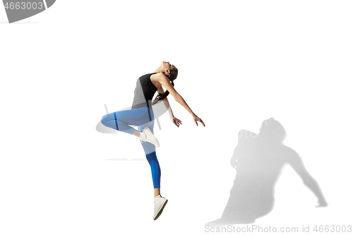 Image of Beautiful young female athlete stretching on white studio background with shadows