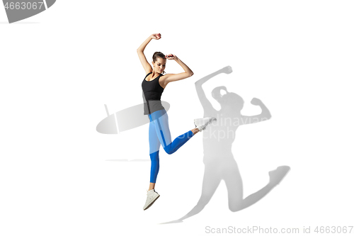 Image of Beautiful young female athlete stretching on white studio background with shadows