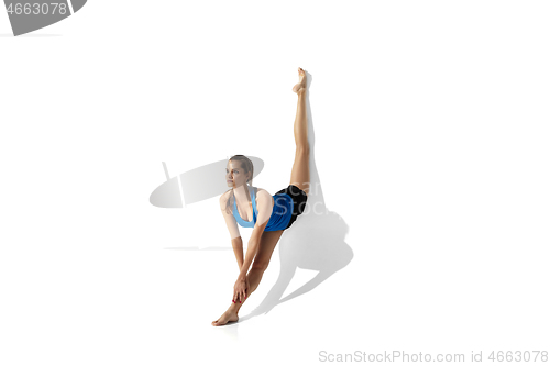 Image of Beautiful young female athlete stretching on white studio background with shadows