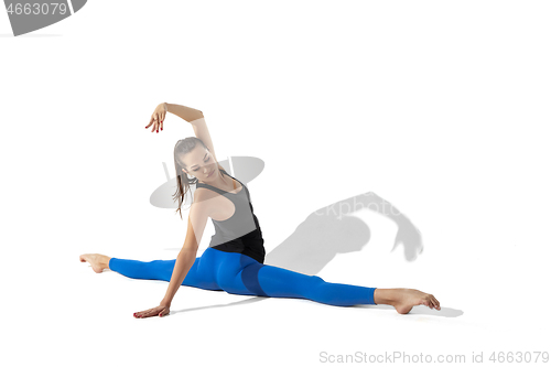 Image of Beautiful young female athlete stretching on white studio background with shadows