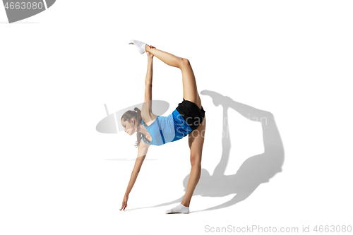 Image of Beautiful young female athlete stretching on white studio background with shadows