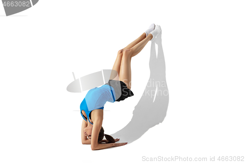 Image of Beautiful young female athlete stretching on white studio background with shadows