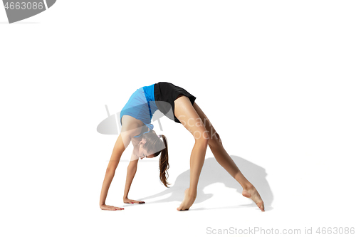 Image of Beautiful young female athlete stretching on white studio background with shadows