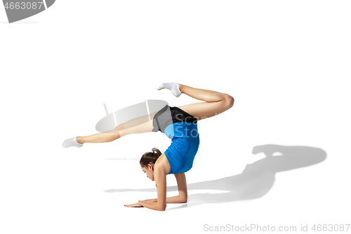 Image of Beautiful young female athlete stretching on white studio background with shadows