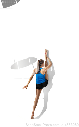 Image of Beautiful young female athlete stretching on white studio background with shadows