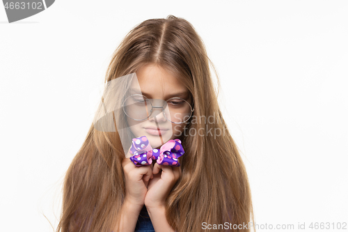 Image of Girl sadly looks at the blue bow in her hands.