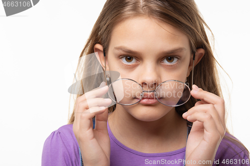 Image of Teen girl takes off glasses, close up