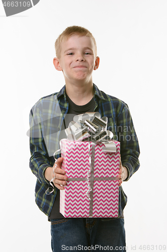 Image of The boy laughs at the present, holding it in his hands