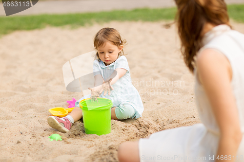 Image of little baby girl plays with toys in sandbox