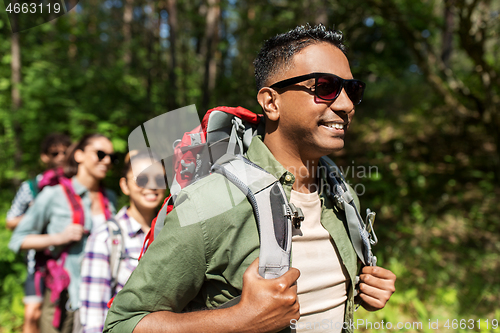 Image of group of friends with backpacks hiking in forest