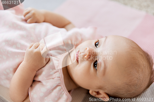 Image of sweet baby girl lying on knitted blanket