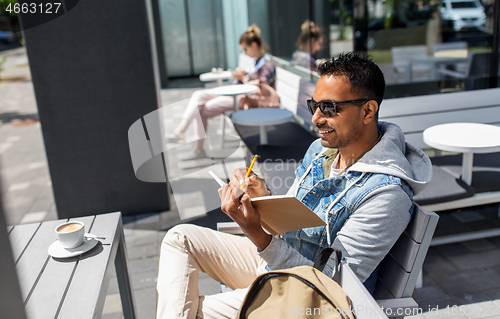 Image of man with notebook and coffee at street cafe