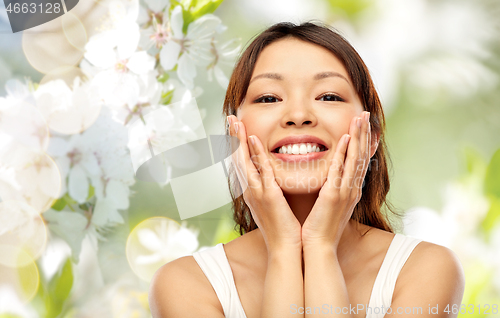 Image of happy smiling young asian woman touching her face