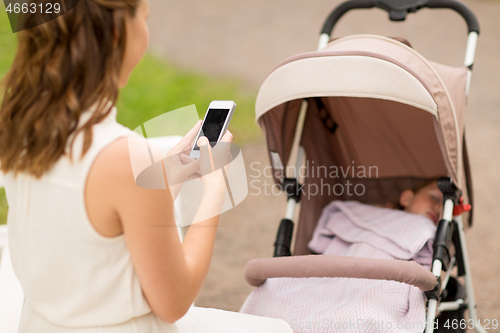 Image of mother with smartphone and baby in stroller