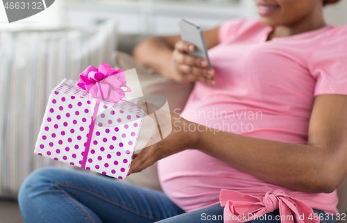 Image of african pregnant woman with smartphone and gift