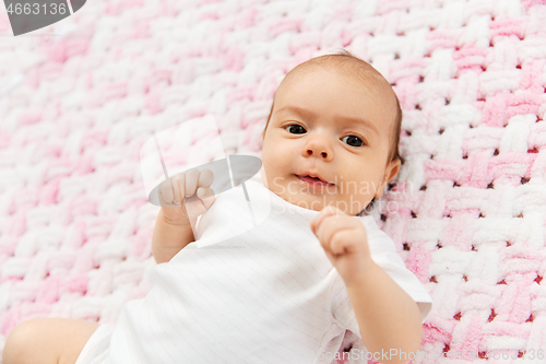 Image of sweet baby girl lying on knitted plush blanket