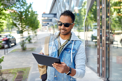 Image of man with tablet pc and backpack on city street