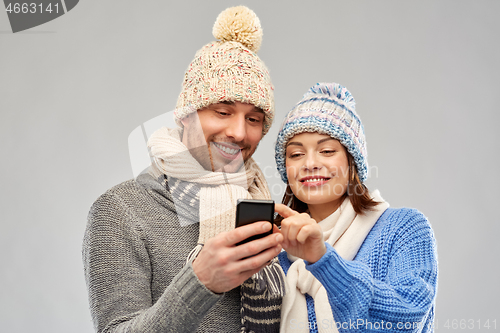 Image of happy couple in winter clothes with smartphone