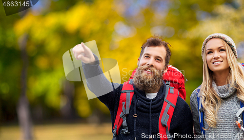 Image of smiling couple with backpacks hiking in autumn