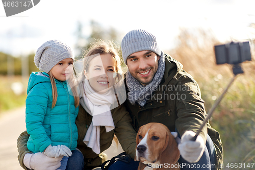 Image of happy family with dog taking selfie in autumn