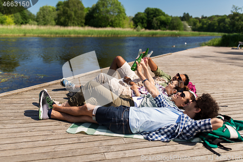 Image of friends drinking beer and cider on lake pier