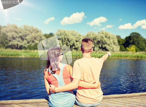 Image of happy couple pointing finger on summer river berth