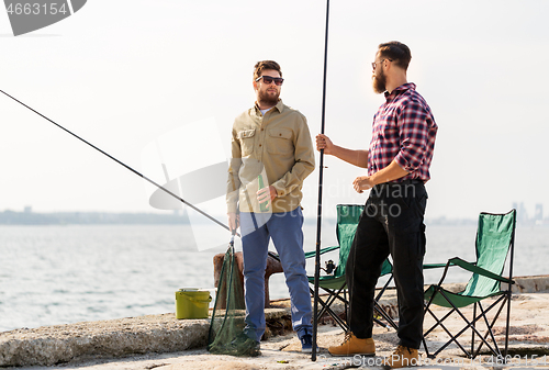 Image of male friends with fishing rods and beer on pier