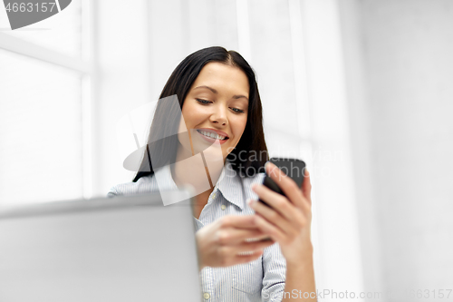 Image of businesswoman using smartphone at office