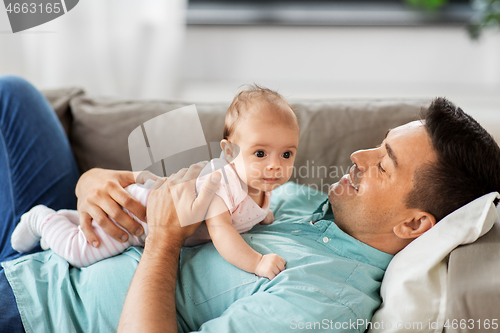 Image of middle aged father with baby lying on sofa at home