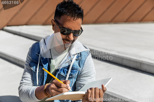 Image of indian man with notebook or sketchbook on roof top