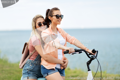 Image of teenage girls or friends riding bicycle in summer