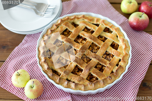 Image of apple pie in baking mold on wooden table