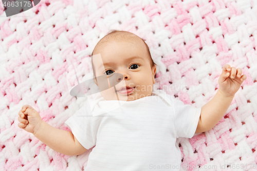 Image of sweet baby girl lying on knitted plush blanket