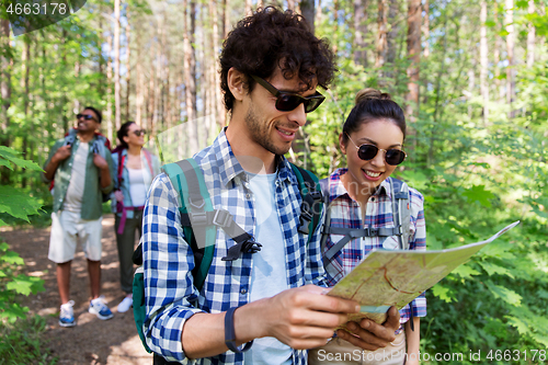 Image of friends with map and backpacks hiking in forest