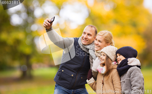 Image of happy family with camera in autumn park