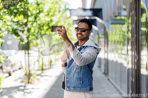 Image of indian man taking selfie by smartphone in city