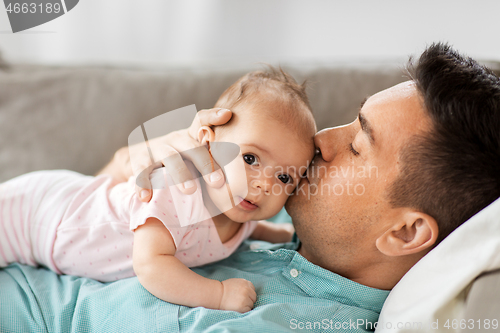 Image of middle aged father kissing baby daughter at home